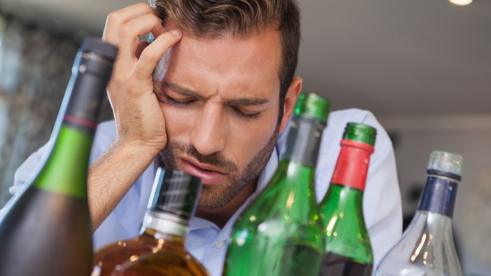 Alcohol Withdrawal and Detox North Jersey Recovery Center - A man is lying in bed where he is experiencing alcohol withdrawal symptoms after binge drinking for a long period of time, and is debating taking Adderall for alcohol withdrawal to ease his symptoms but is unsure if this is a smart idea.