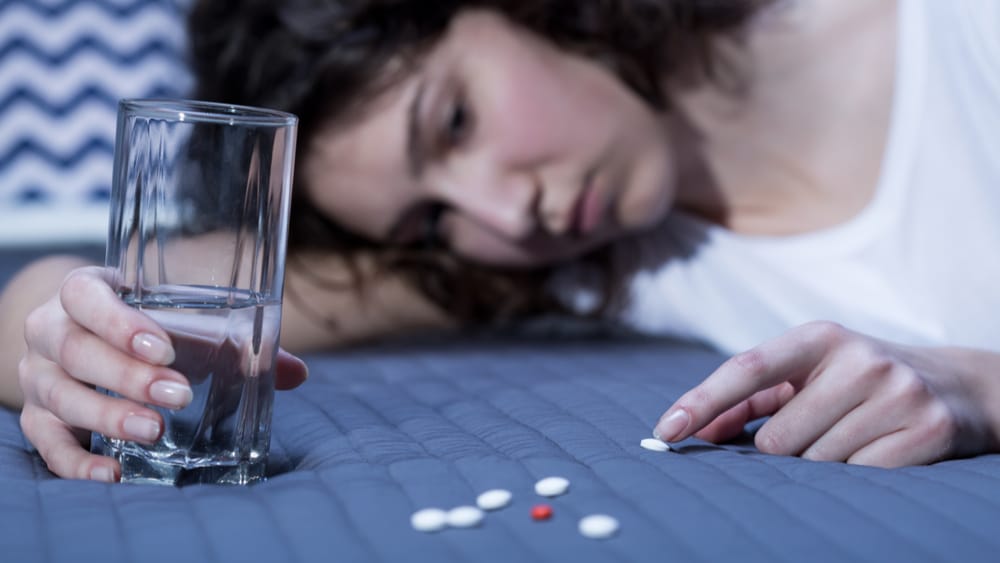 Oxycodone Addiction North Jersey Recovery Center - A woman struggling with an oxycodone addiction lays in bed counting the number of prescription pills she has left, while realizing that she may need to seek out treatment for her addiction.