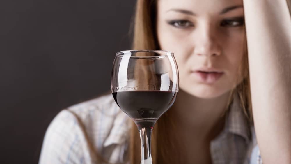 Alcohol and the Liver - North Jersey Recovery - A woman sits and stars at her glass of red wine.