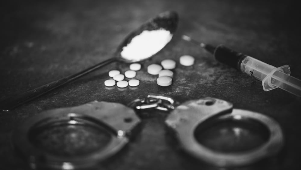 Controlled Substances Act and Drug Scheduling North Jersey Recovery - Image of handcuffs, a spoon with white powder in it and a heroin needle.