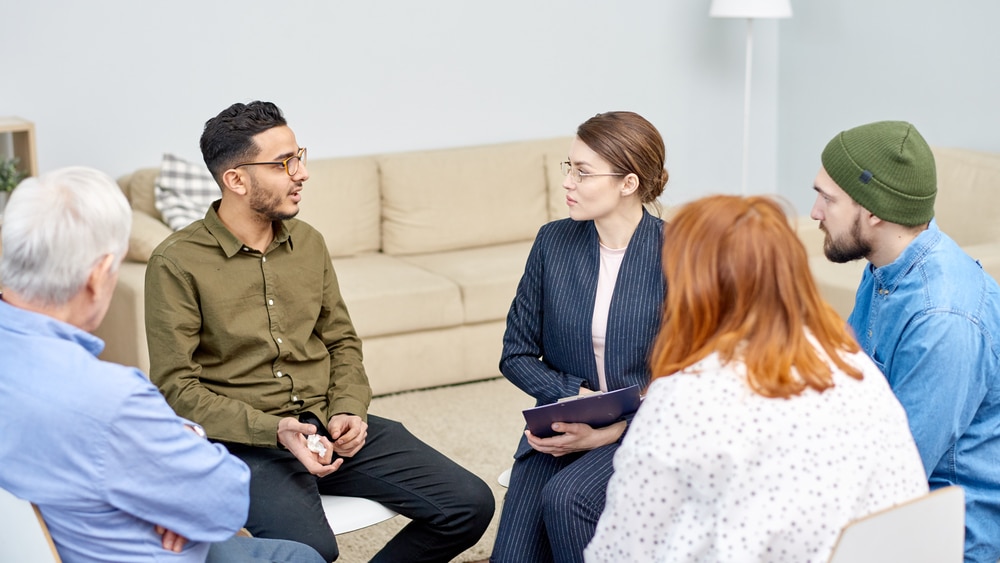 Is Alcohol a Depressant? North Jersey Recovery Center - A group of individuals attending an inpatient alcohol rehab for alcoholism is engaging in a group therapy session and discussing topics, such as: "Is alcohol a depressant?" as well as other helpful tools and resources to support each other as they continue on their journeys to recovery.