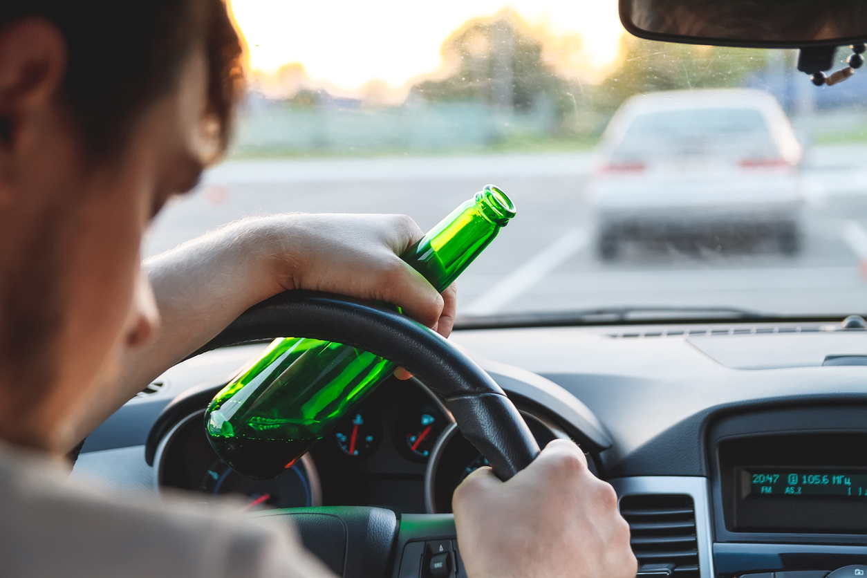 Man driving drunk with beer bottle in hand - DWI on the 4th of July
